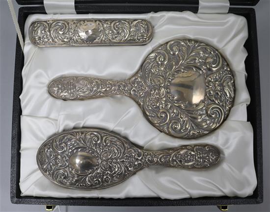A cased 1970s repousse silver three piece dressing table set.